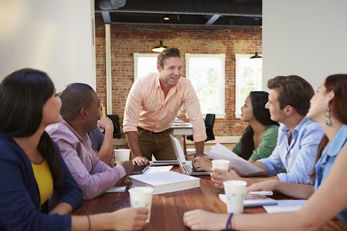 Male Boss Addressing Office Workers At Meeting Male Boss Addressing Office Workers At Meeting